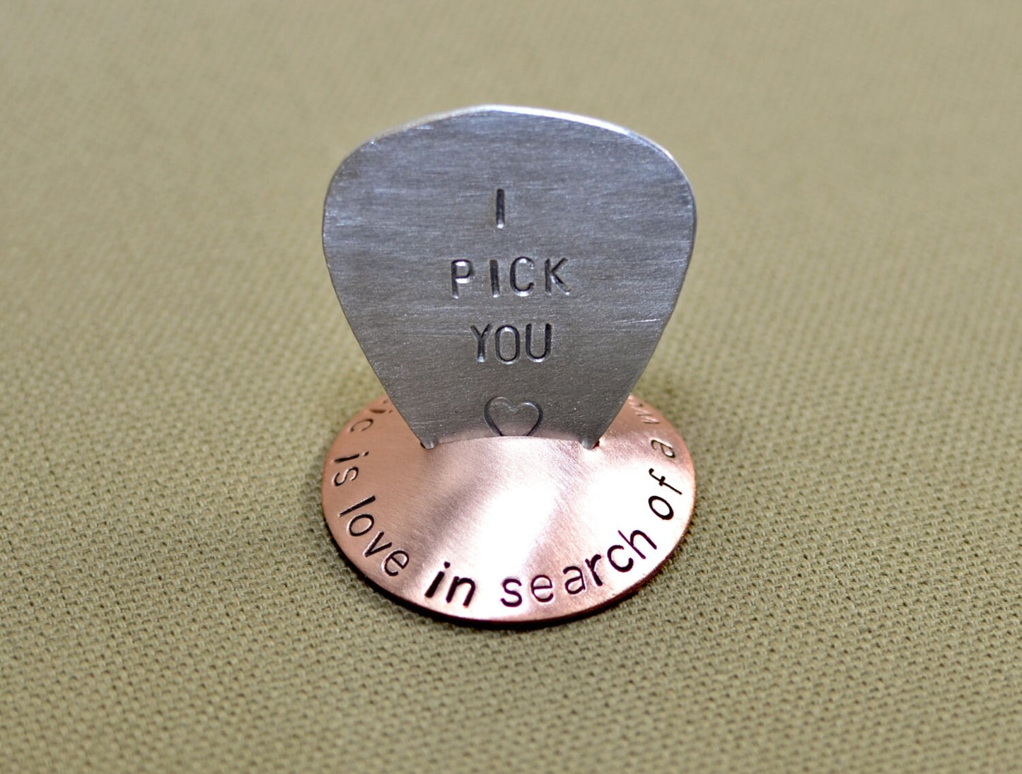 Copper guitar pick stand with "music is love in search of a word