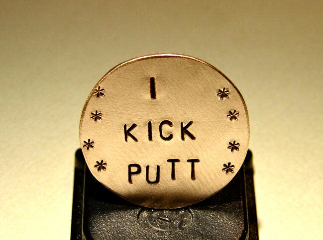 Bronze golf ball marker with I kick putt