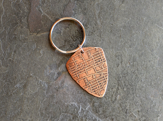 Copper key ring guitar pick with music notes