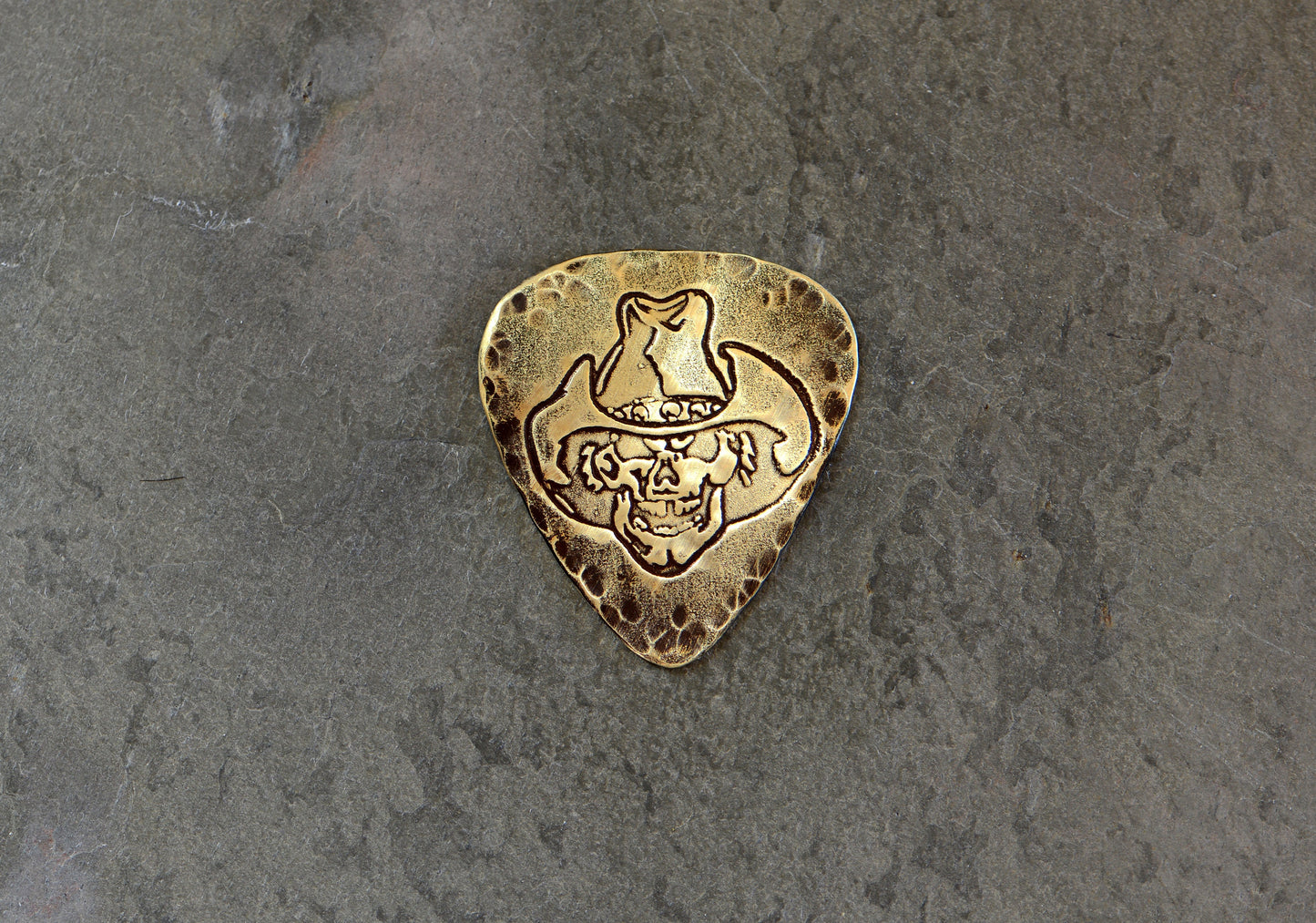 Brass guitar pick rocking a skull with cowboy hat