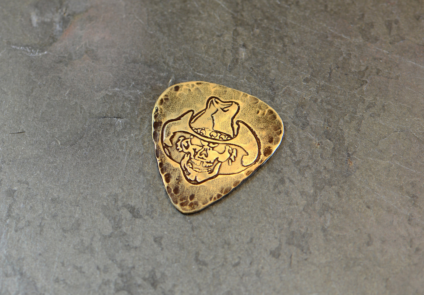 Brass guitar pick rocking a skull with cowboy hat