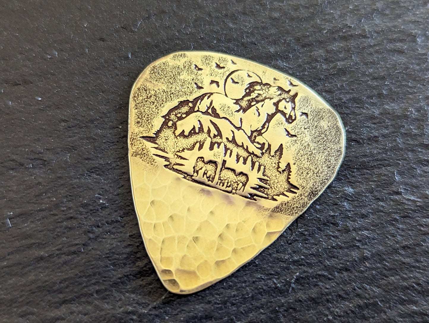 Brass guitar pick with forest and horses - playable brass plectrum