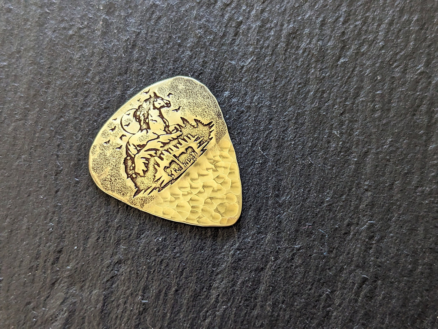 Brass guitar pick with forest and horses - playable brass plectrum