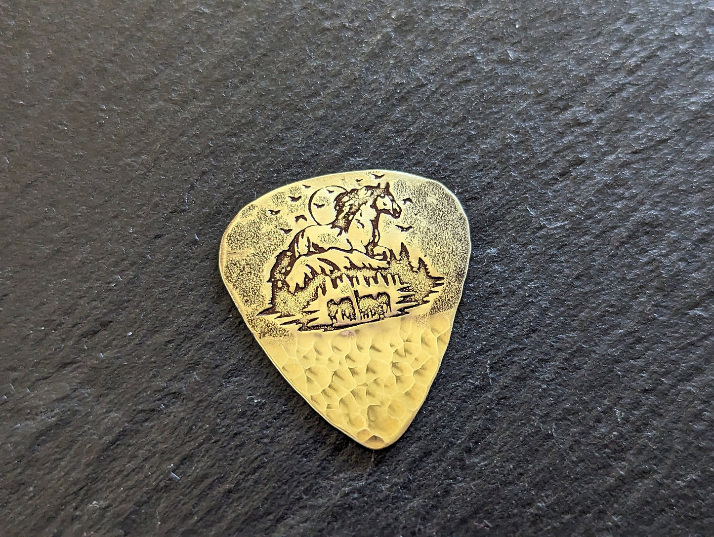 Brass guitar pick with forest and horses - playable brass plectrum