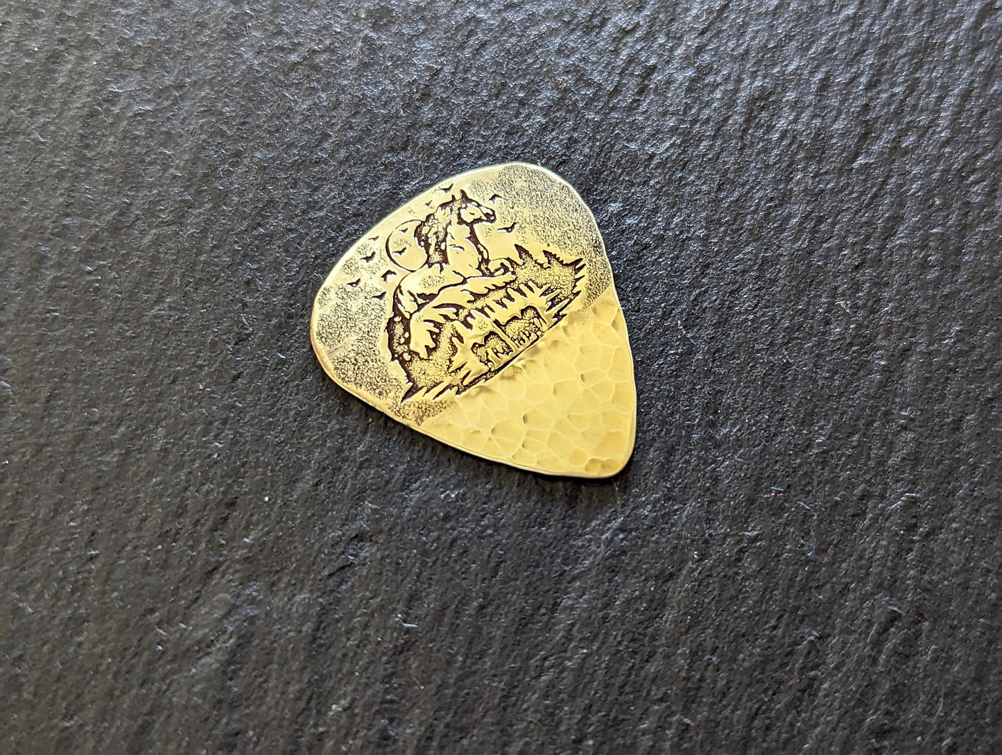 Brass guitar pick with forest and horses - playable brass plectrum