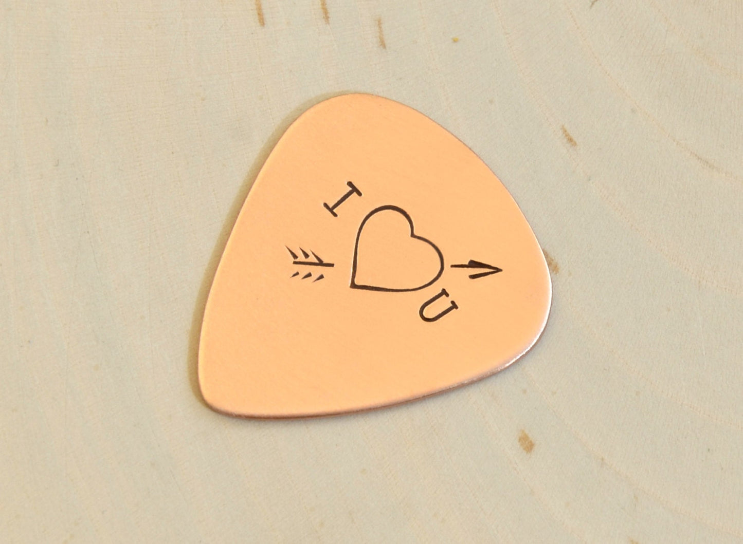 I love you copper guitar pick with Cupid's arrow of love straight through the heart