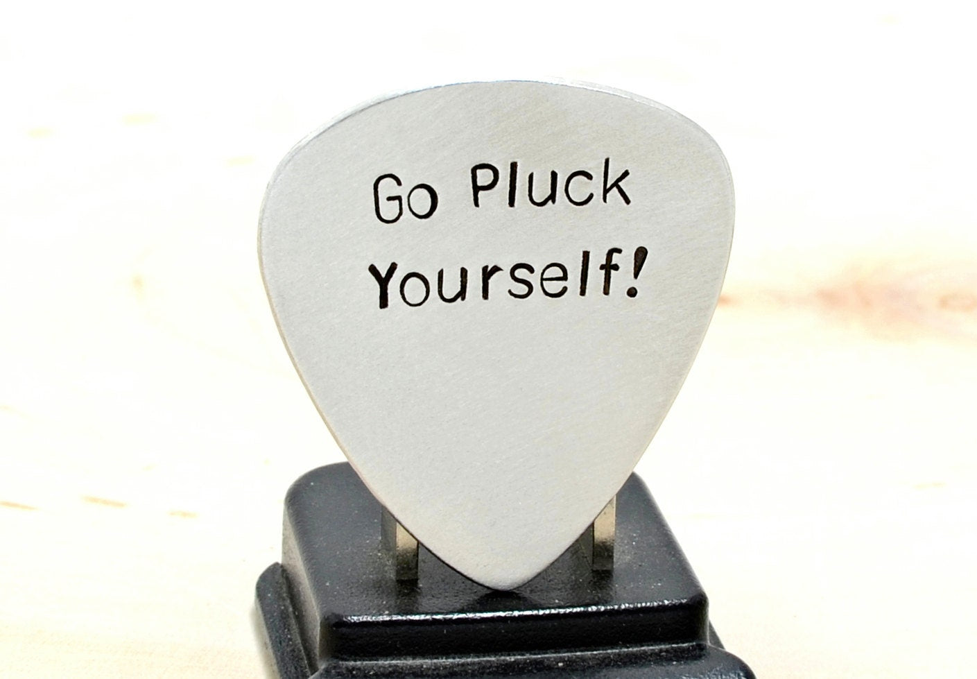 Silver guitar pick with Go Pluck Yourself