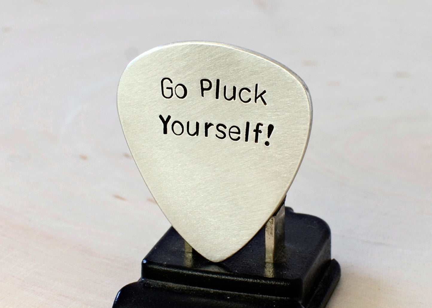 Silver guitar pick with Go Pluck Yourself
