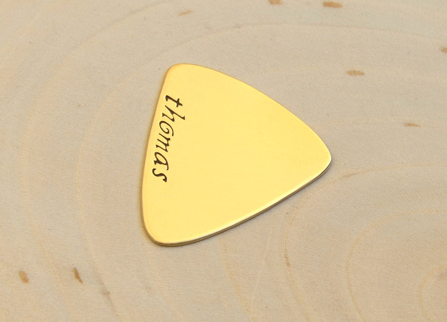 Brass triangular guitar pick with custom names and engraving