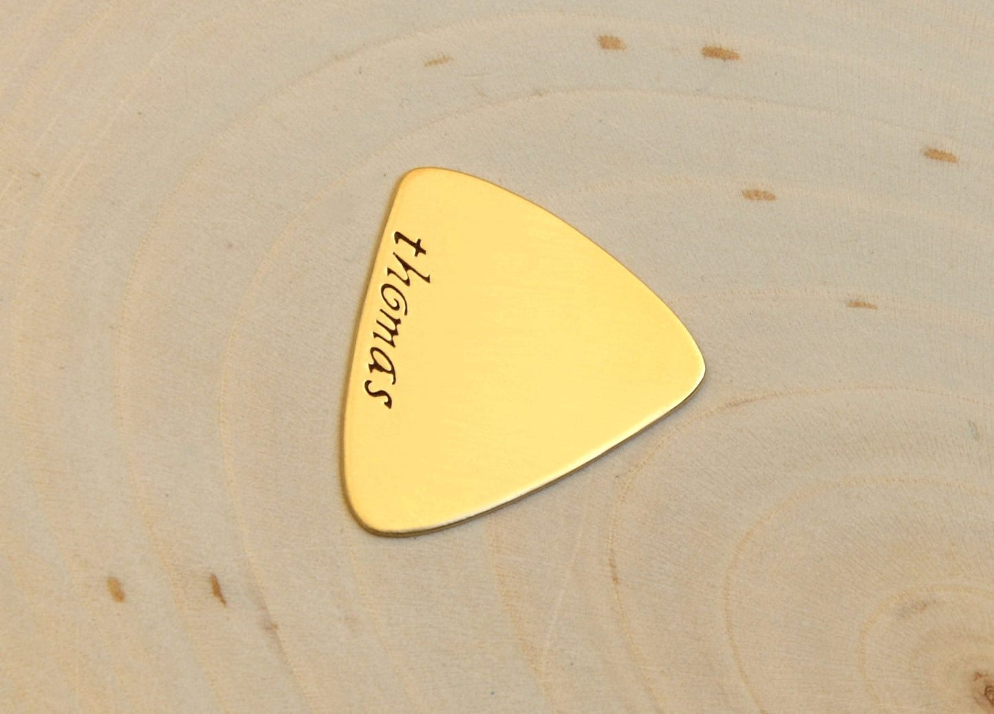 Brass triangular guitar pick with custom names and engraving