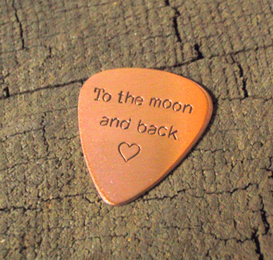 Copper guitar pick stamped with to the moon and back