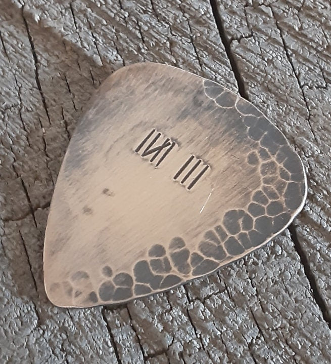 Distressed and rustic bronze guitar pick with tally mark