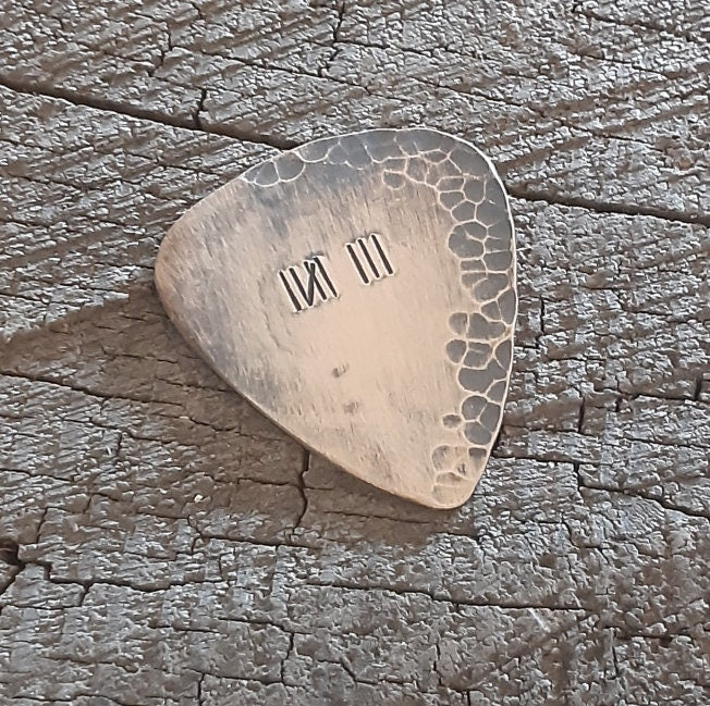 Distressed and rustic bronze guitar pick with tally mark
