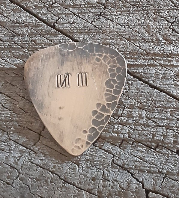 Distressed and rustic bronze guitar pick with tally mark