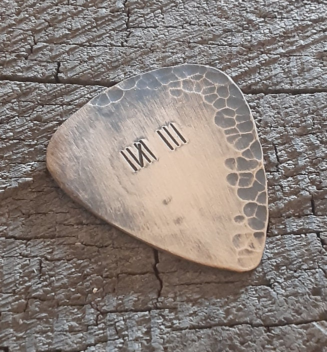 Distressed and rustic bronze guitar pick with tally mark