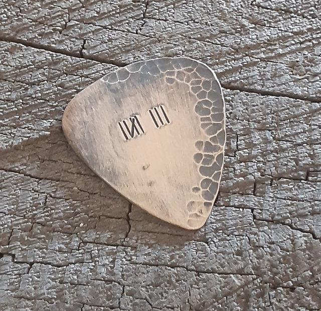 Distressed and rustic bronze guitar pick with tally mark
