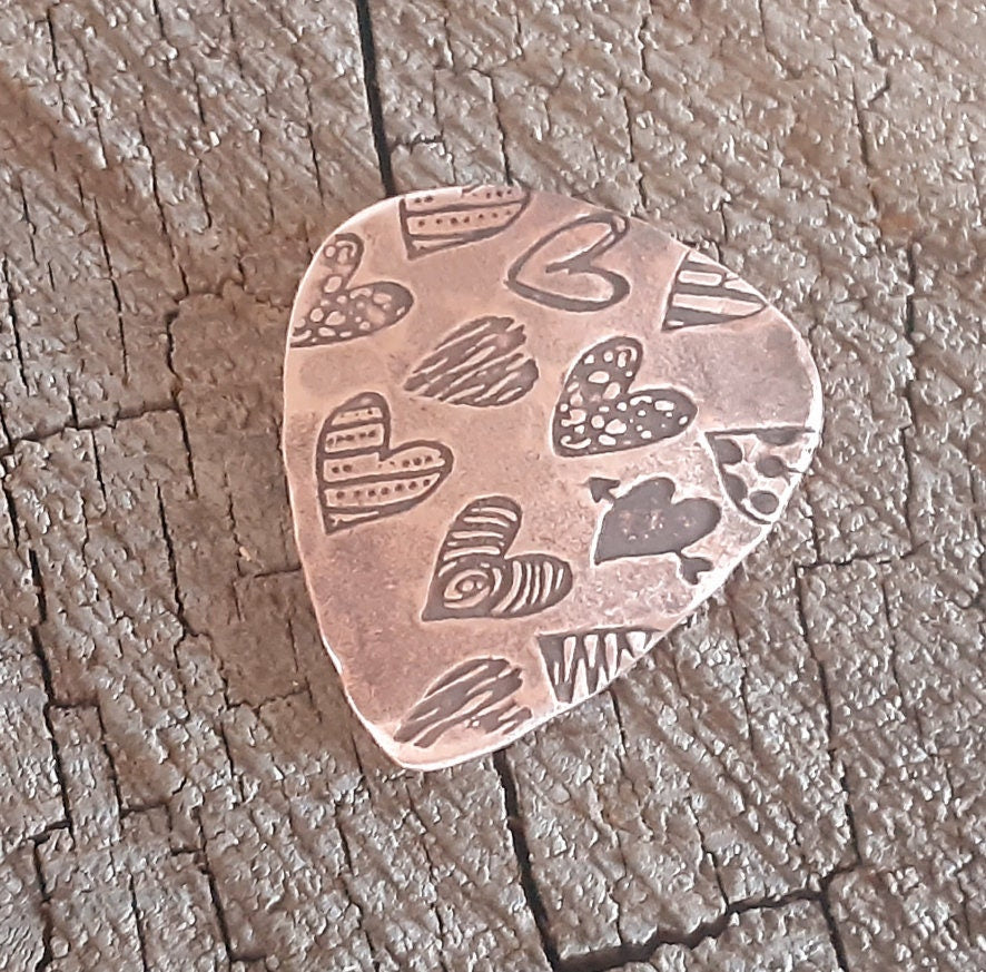 Copper guitar pick with hearts and hammered patterning