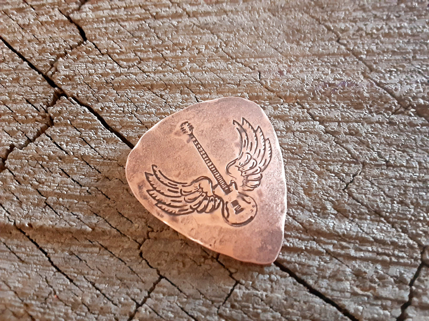 Winged guitar on copper guitar pick