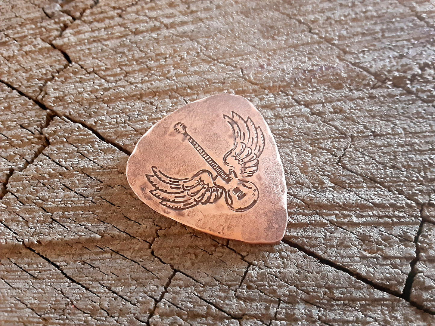 Winged guitar on copper guitar pick