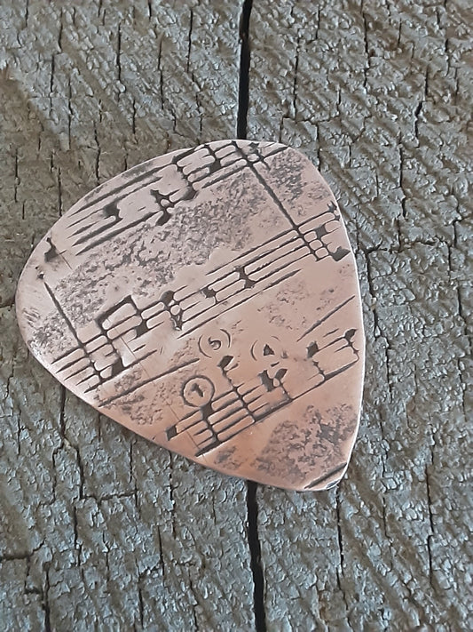 Copper guitar pick with music notes