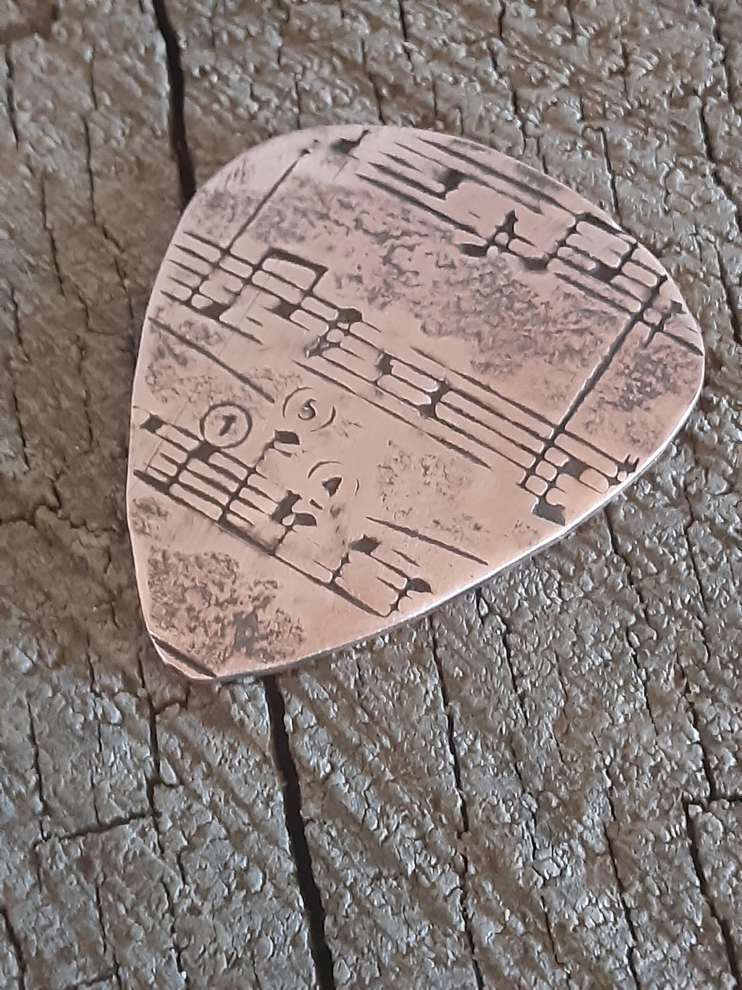 Copper guitar pick with music notes