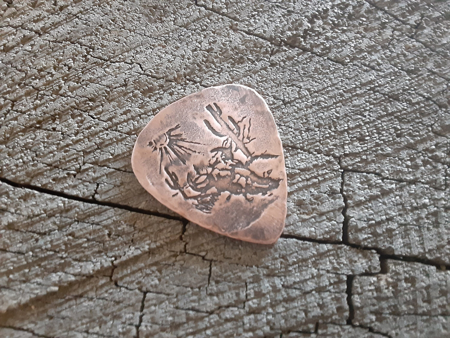 Copper guitar pick with desert steer skull design