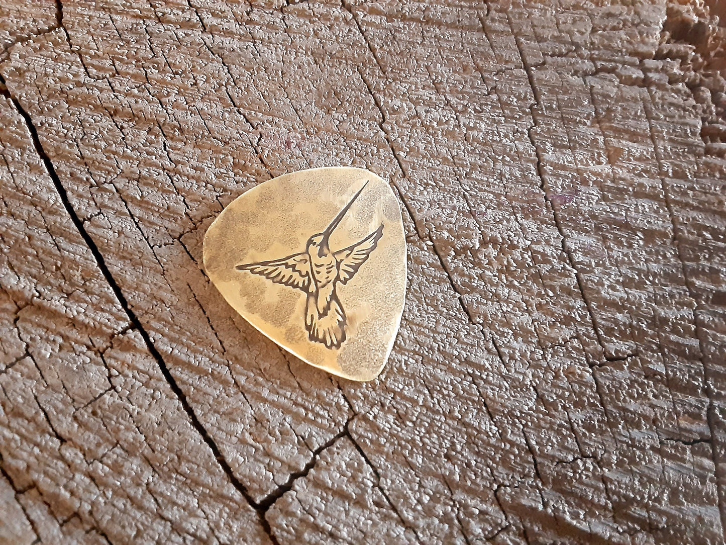 Guitar pick in brass with hummingbird
