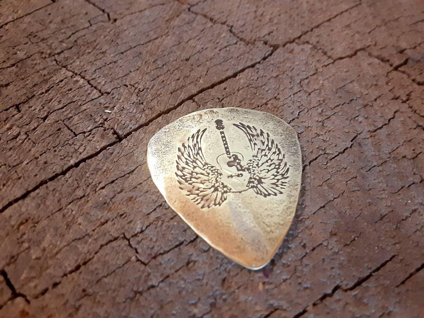 Winged guitar on brass guitar pick