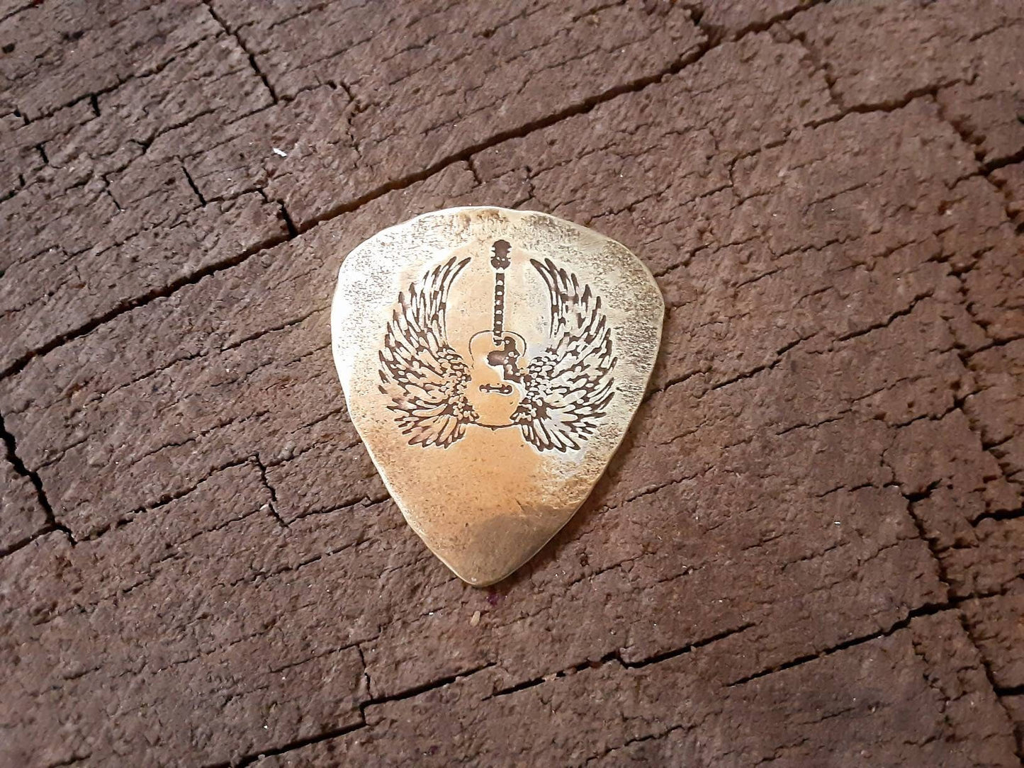 Winged guitar on brass guitar pick