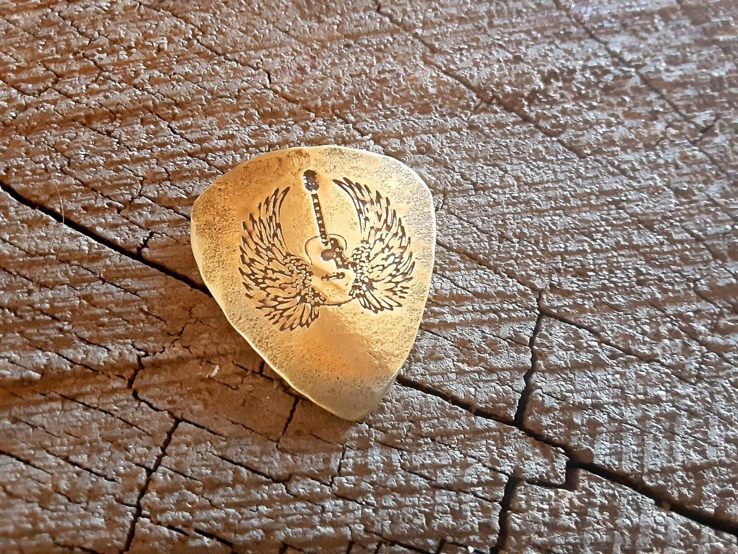 Winged guitar on brass guitar pick