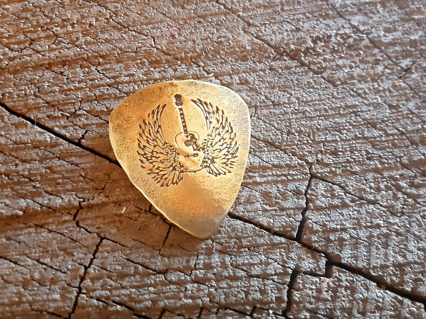 Winged guitar on brass guitar pick