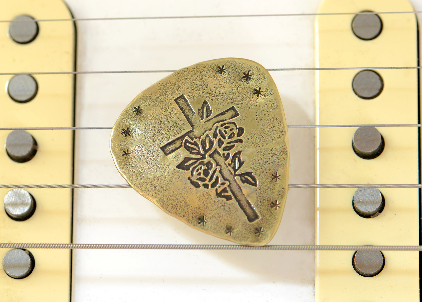 Playable brass guitar pick with cross and roses