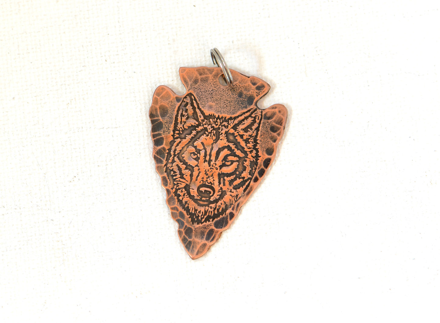 Rustic copper arrowhead pendant with wolf design