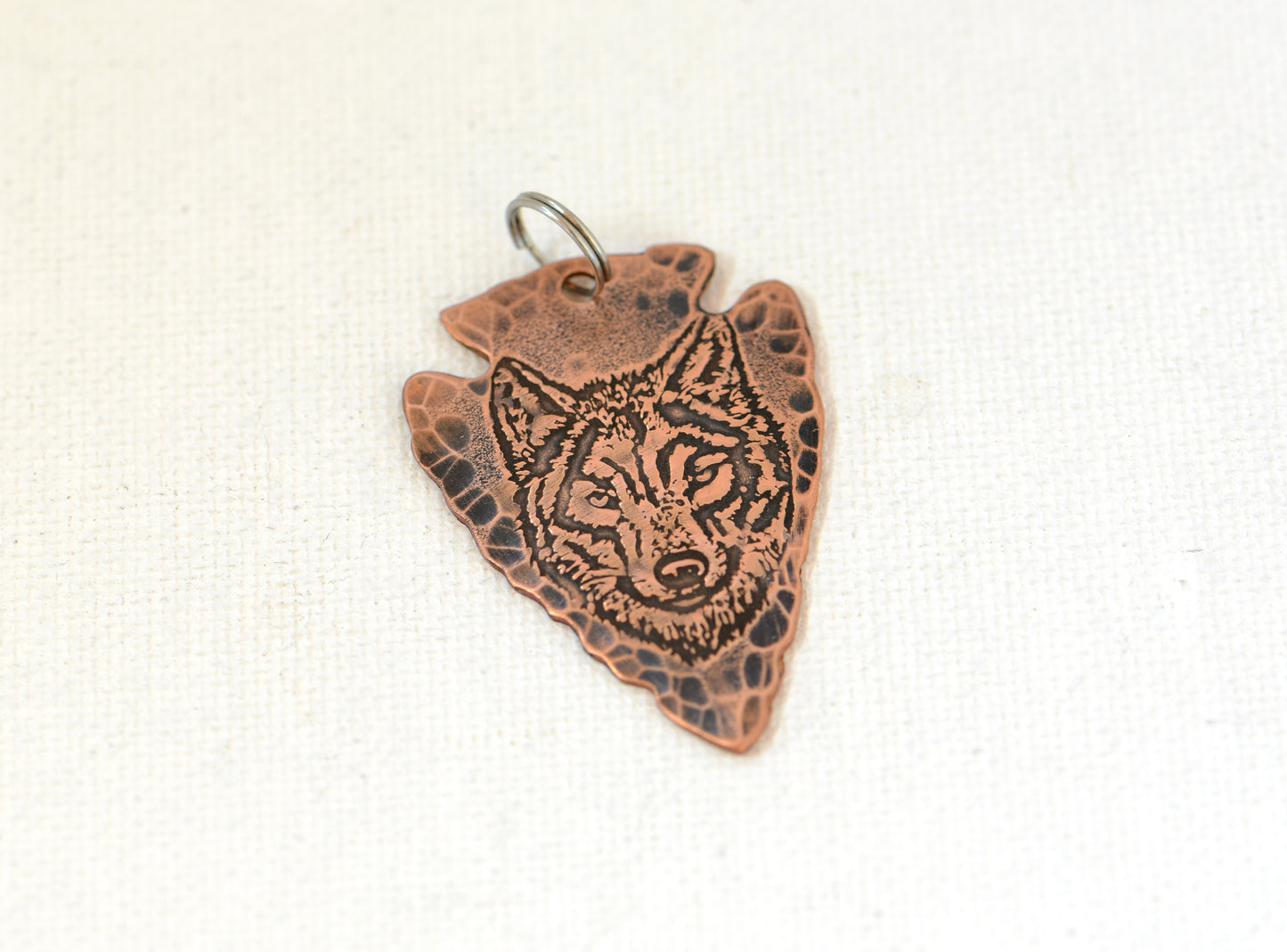 Rustic copper arrowhead pendant with wolf design