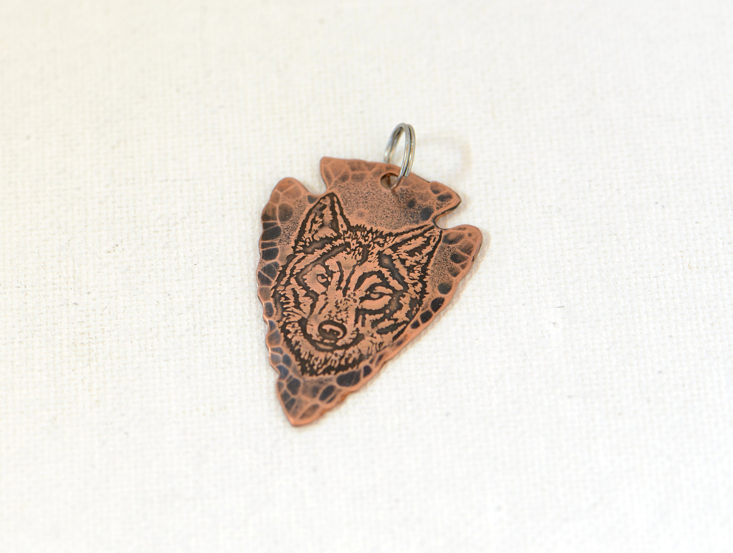 Rustic copper arrowhead pendant with wolf design