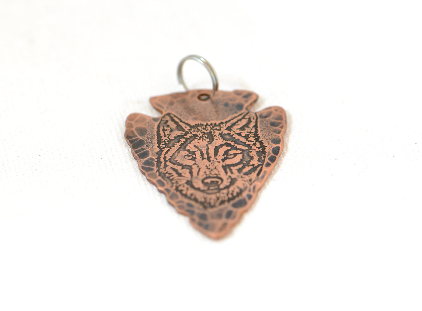 Rustic copper arrowhead pendant with wolf design