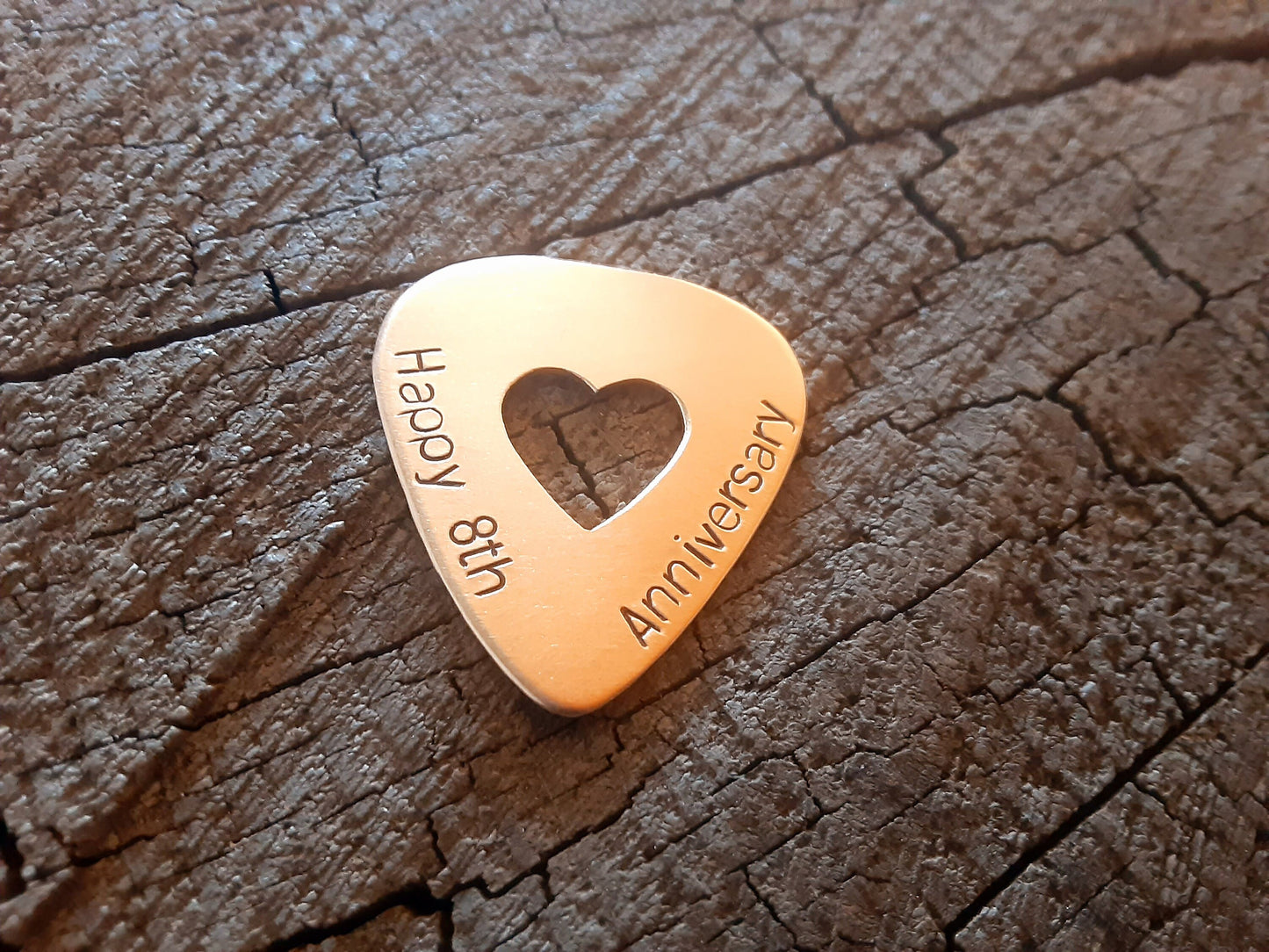 Anniversary bronze guitar pick with cutout heart