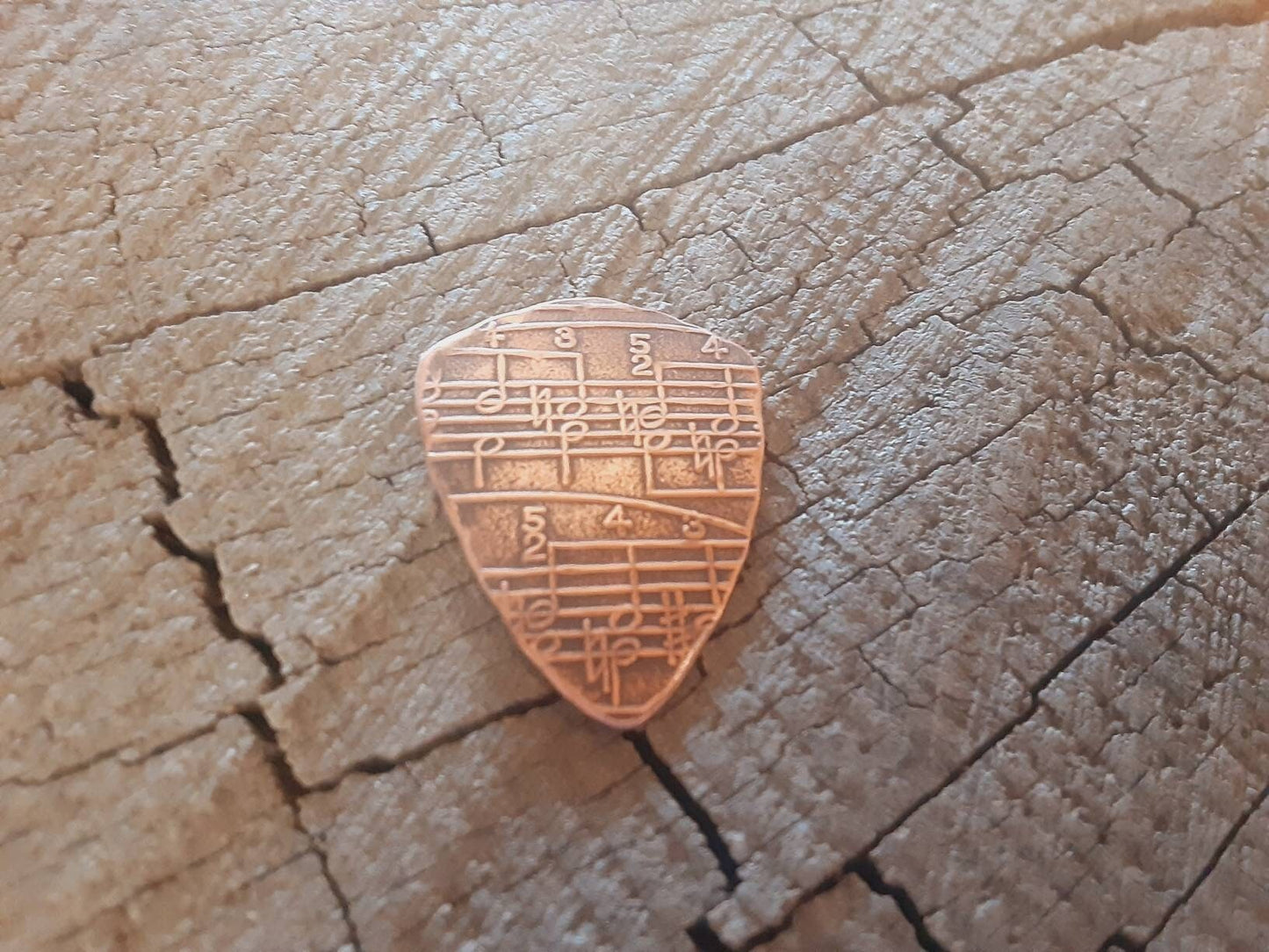 Copper shield shape guitar pick with music notes