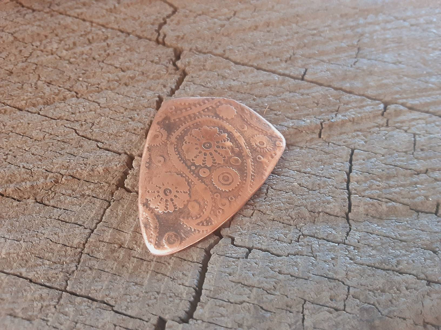 Guitar pick with paisley pattern in copper