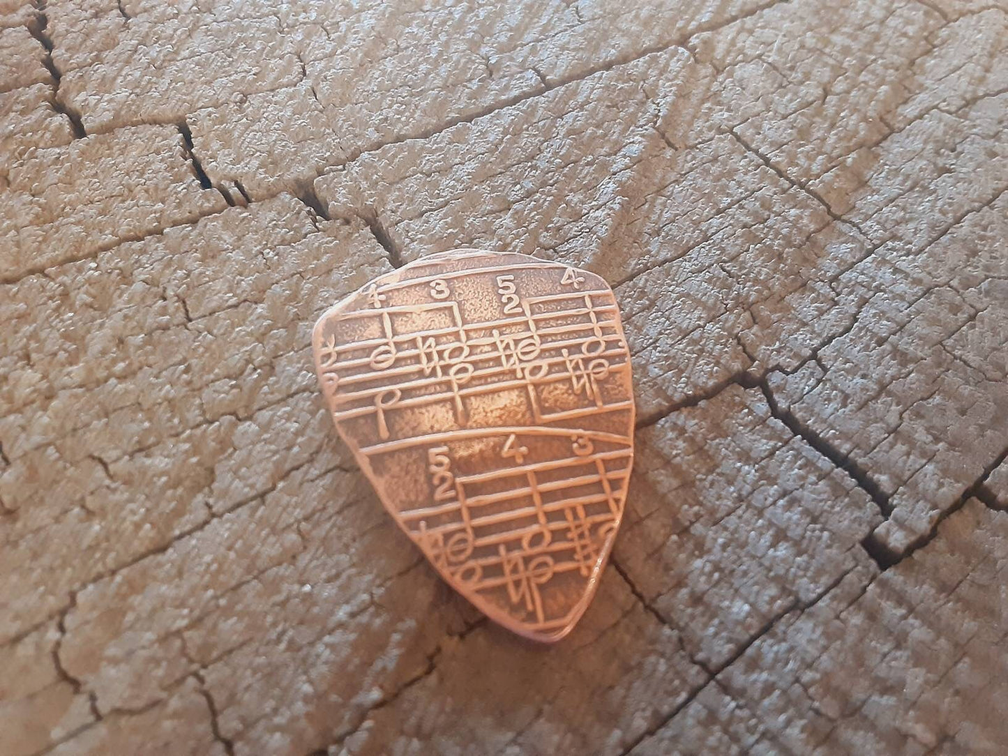 Copper shield shape guitar pick with music notes