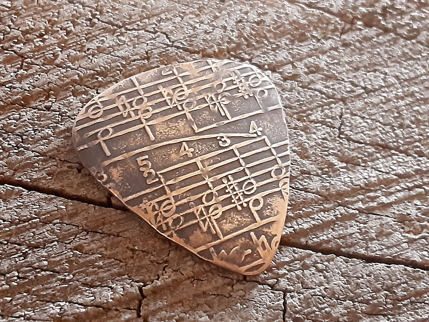 Guitar pick in Bronze with music notes