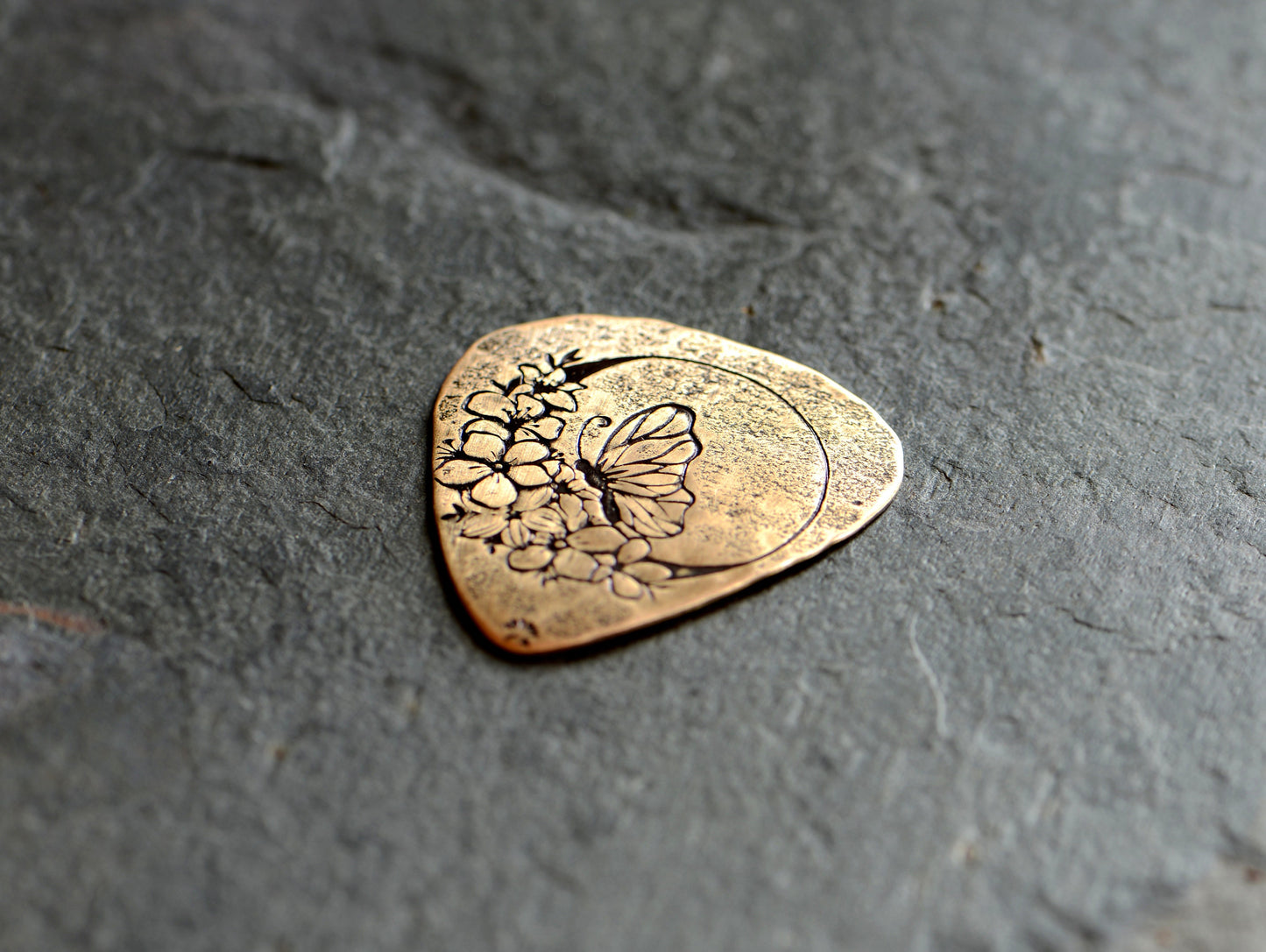 Butterfly moon and flowers on bronze guitar pick