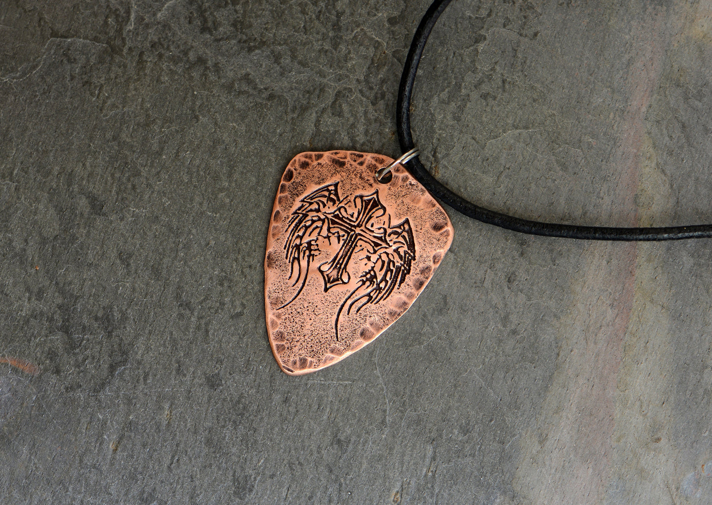 Shield style copper guitar pick necklace featuring a winged cross