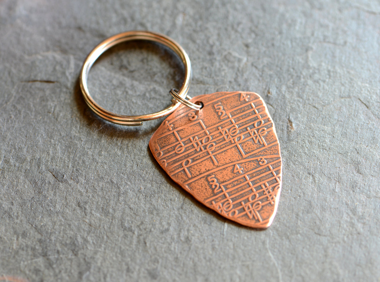 Copper key ring guitar pick with music notes