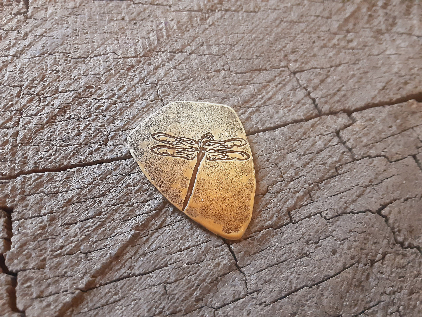 Playable brass guitar pick in shield shape with dragonfly