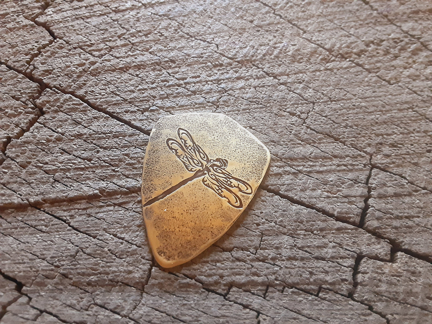 Playable brass guitar pick in shield shape with dragonfly