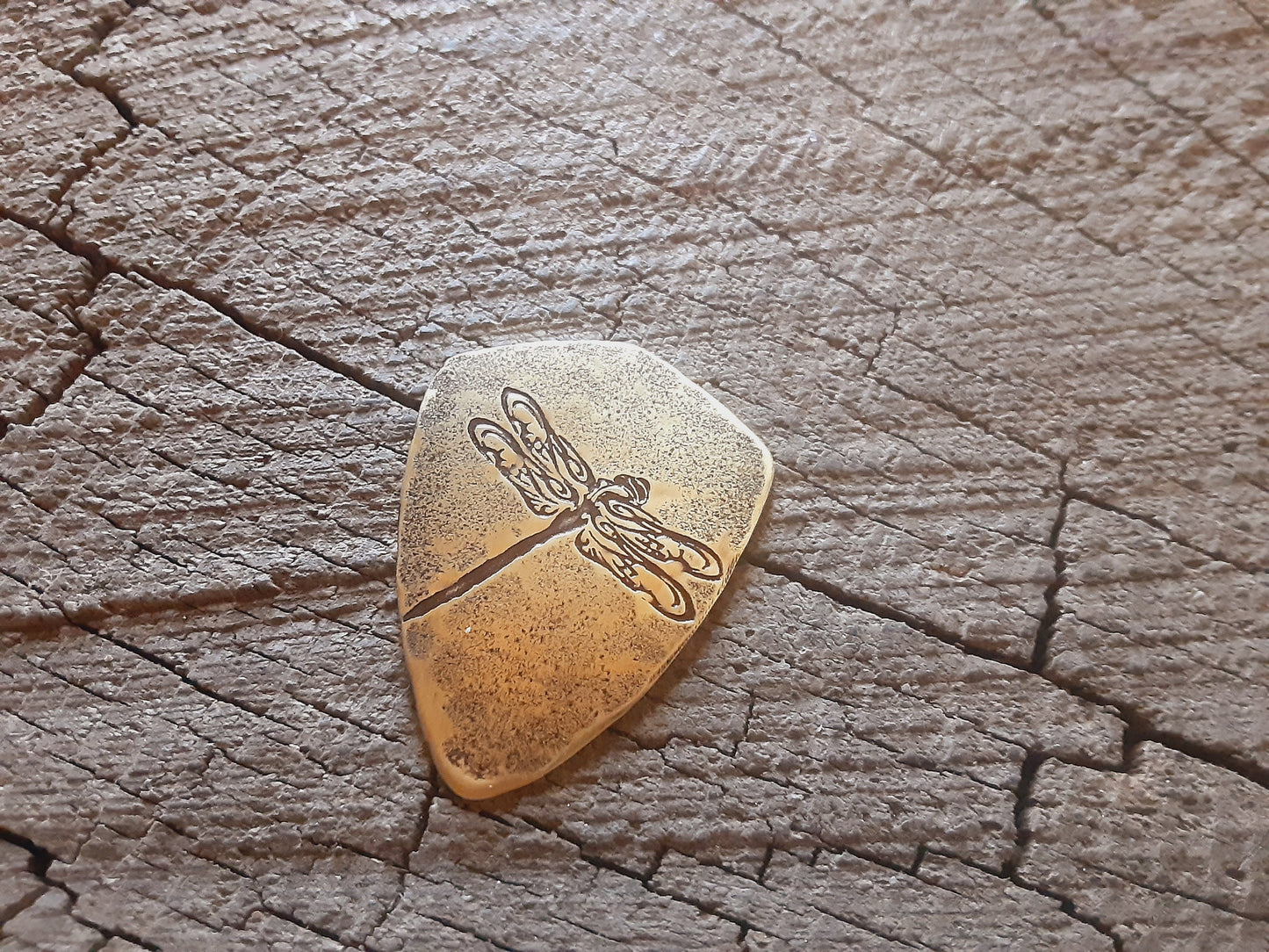 Playable brass guitar pick in shield shape with dragonfly