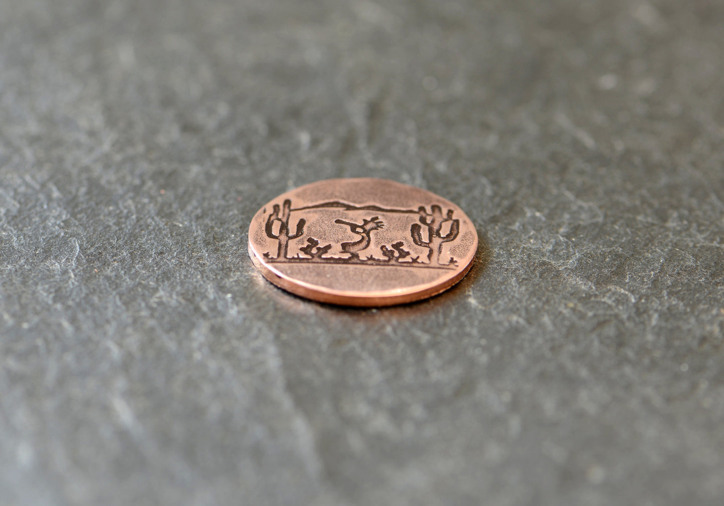 Golf ball marker with saguaro cacti and Kokopelli on copper