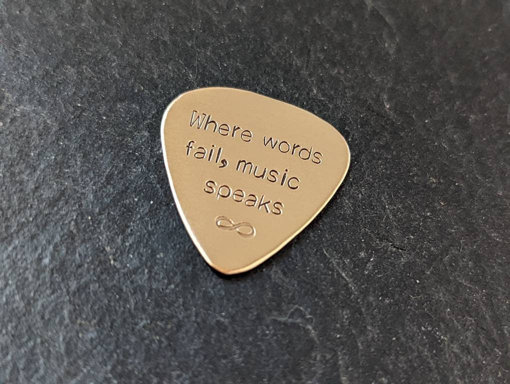 Playable bronze guitar pick stamped with when words fail, music speaks and infinity sign