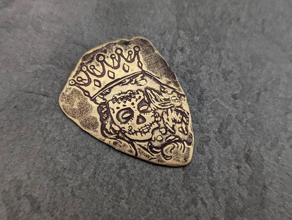 Bronze shield shaped guitar pick with Day of the Dead Theme